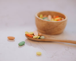 Pills on a wooden bowl and teaspoon.