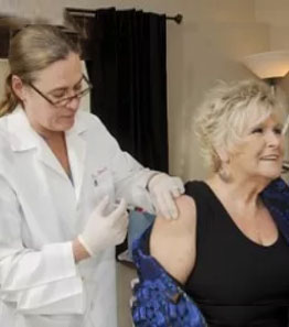 Doctor giving injection vaccine to elderly woman.