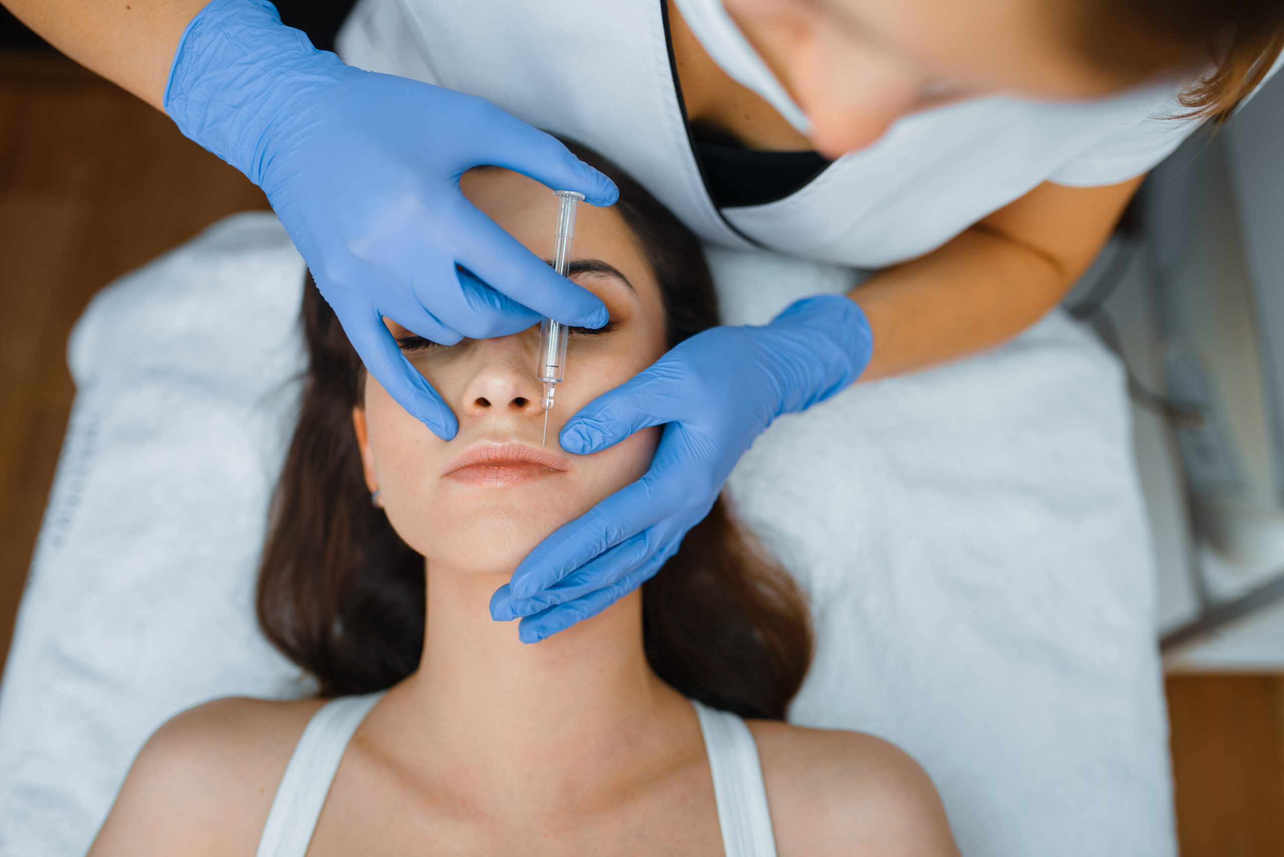 Cosmetician gives face botox injections to patient