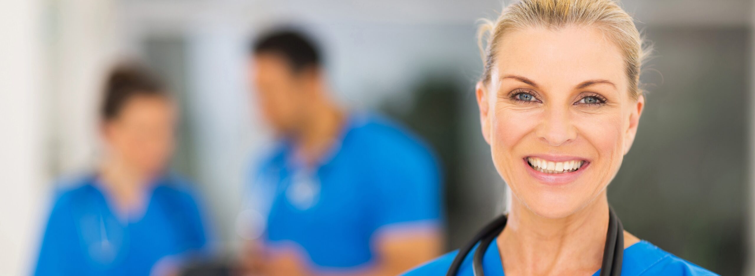 close-up of a female doctor smiling and wearing blue scrubs