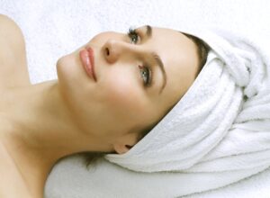 woman lying down with her hair wrapped up in a towel