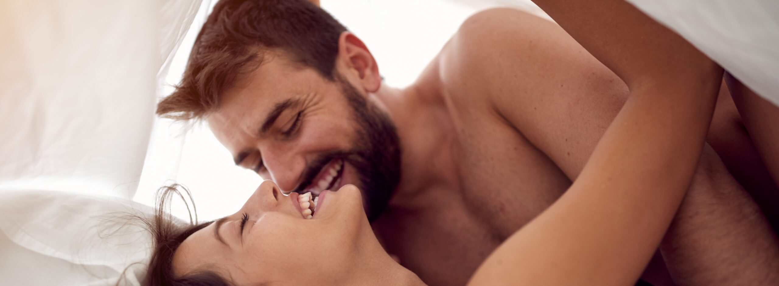 man and woman lying in bed together laughing