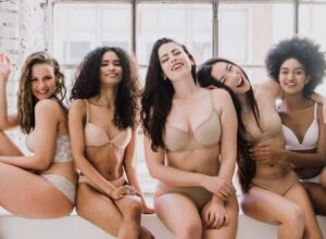 a group of women of different ethnicities posing and laughing in their underwear
